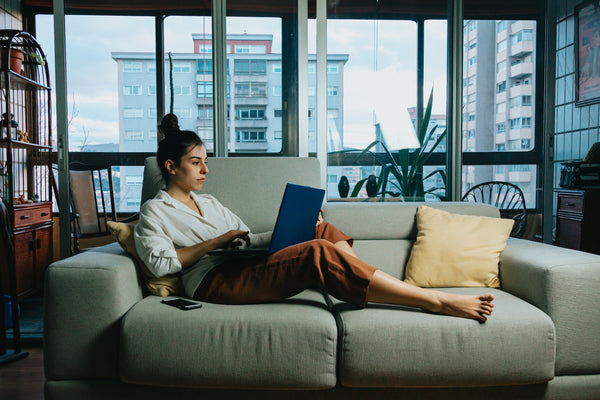 ソファでパソコンを使うパジャマ姿の女性