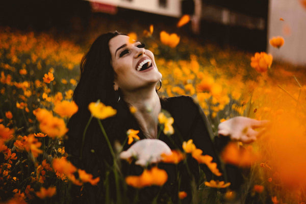 オレンジの花茂みの中で微笑む女性。